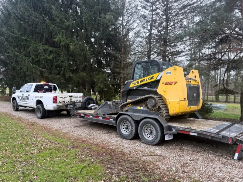 Horvath Lawn and Landscape truck and skid steer on a drainage job near Avon